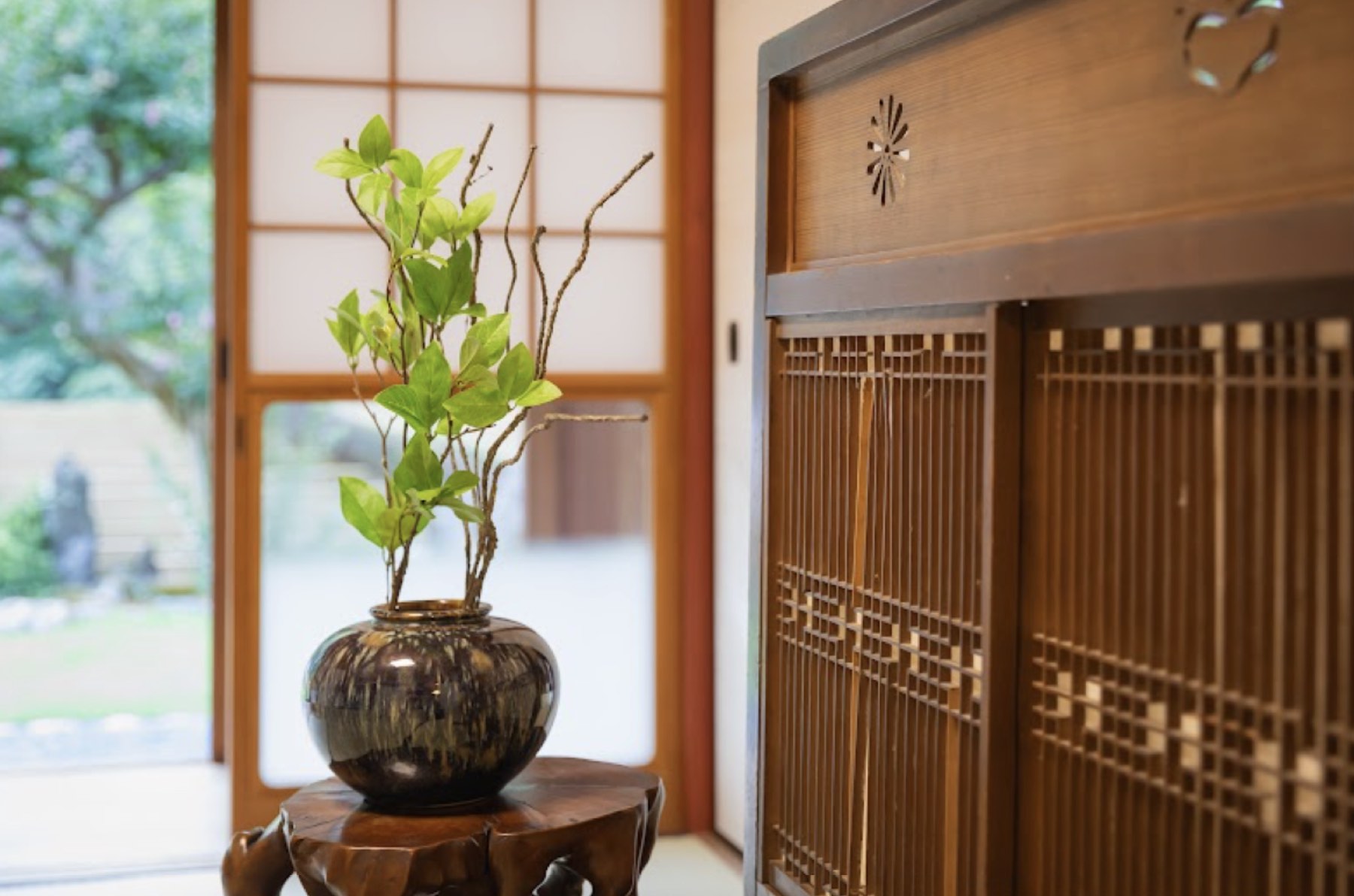 障子のそばの台に置かれた生け花と、組子の建具