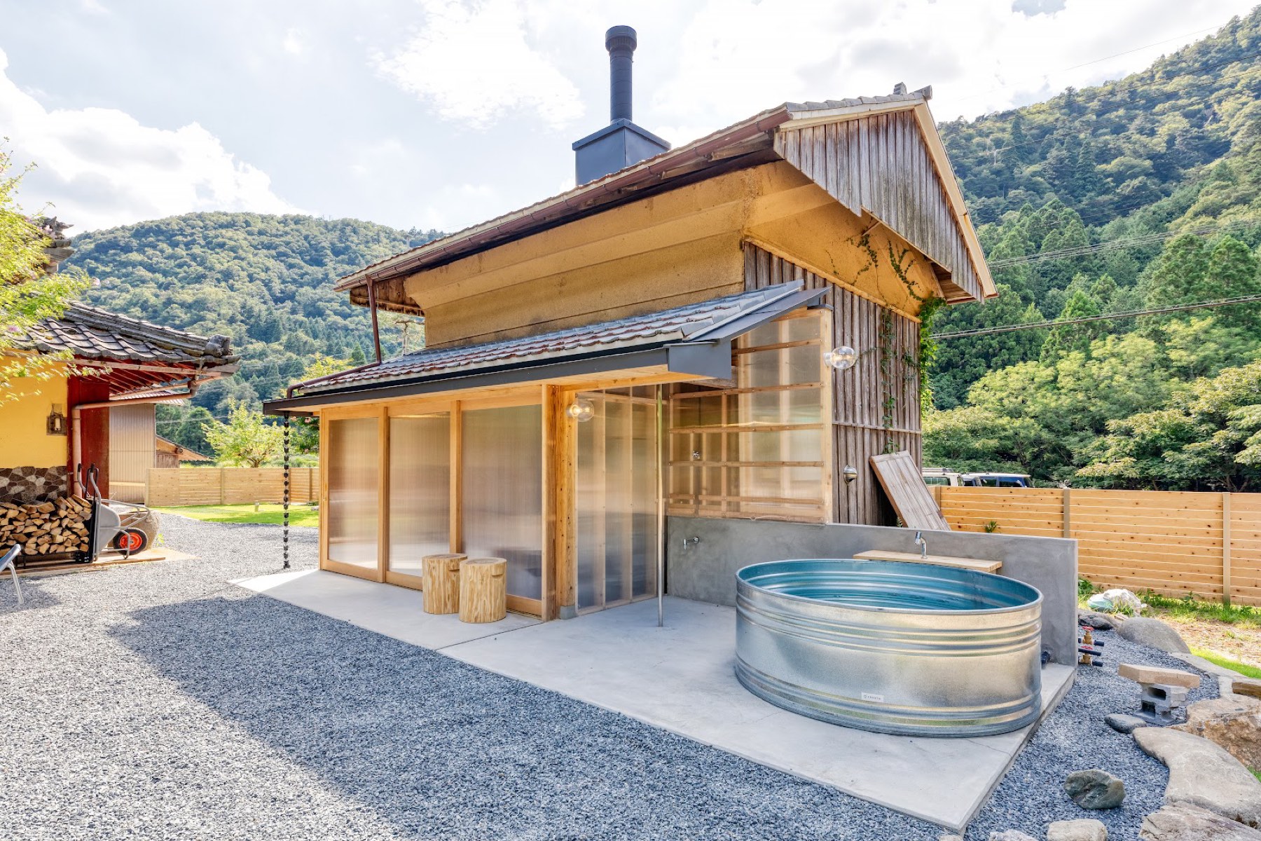 蔵サウナと屋外の水風呂。芝生の庭の向こうに山並み