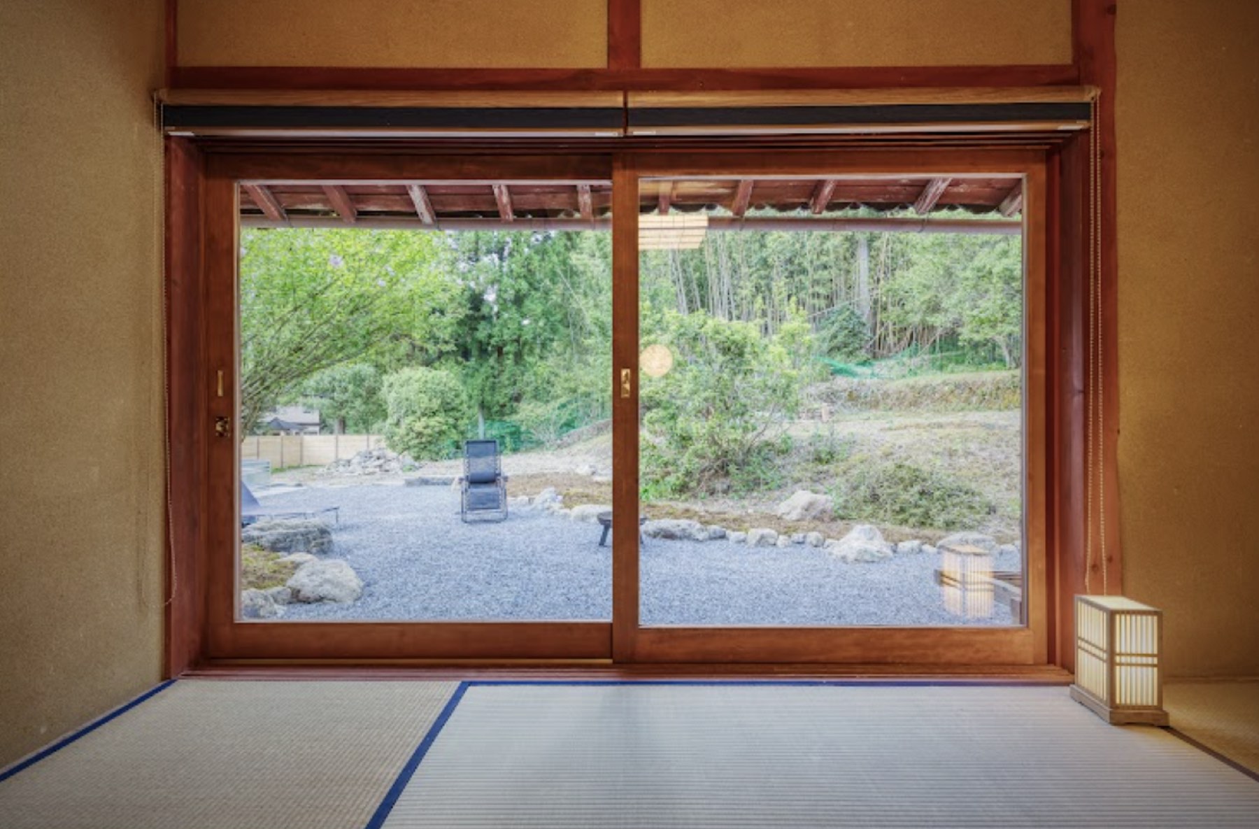 和室から縁側越しに見える庭。障子を開け放った先に木と砂利